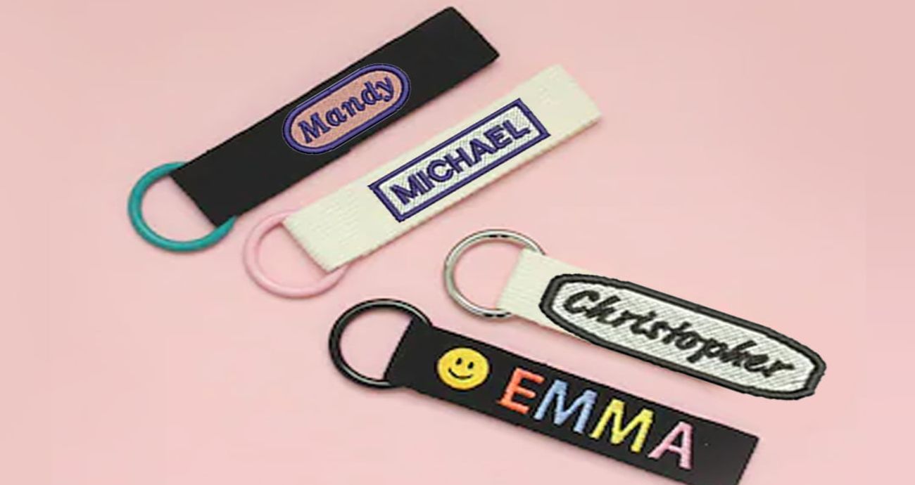 Colorful custom embroidered name badges with keyrings, featuring various names like Mandy, Michael, Christopher, and Emma.